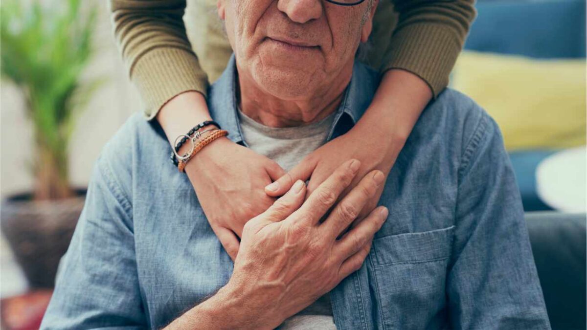 Hands holding elderly male in support and comfort