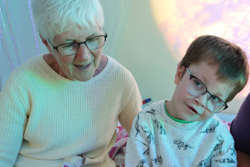 Rosie, a volunteer sat with a child patient reading at Keech Hospice